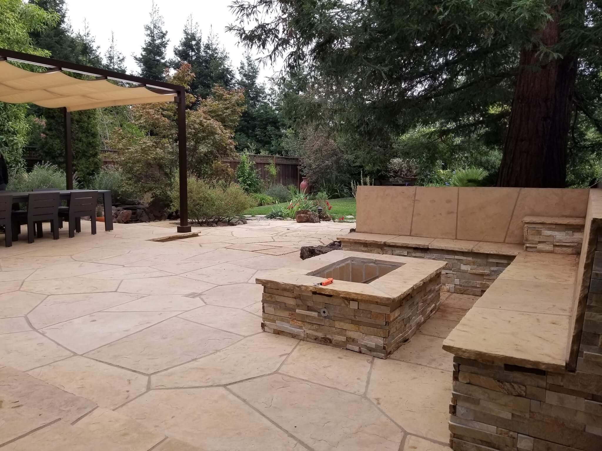 Custom stone fire pit and bench seat with patio and pergola